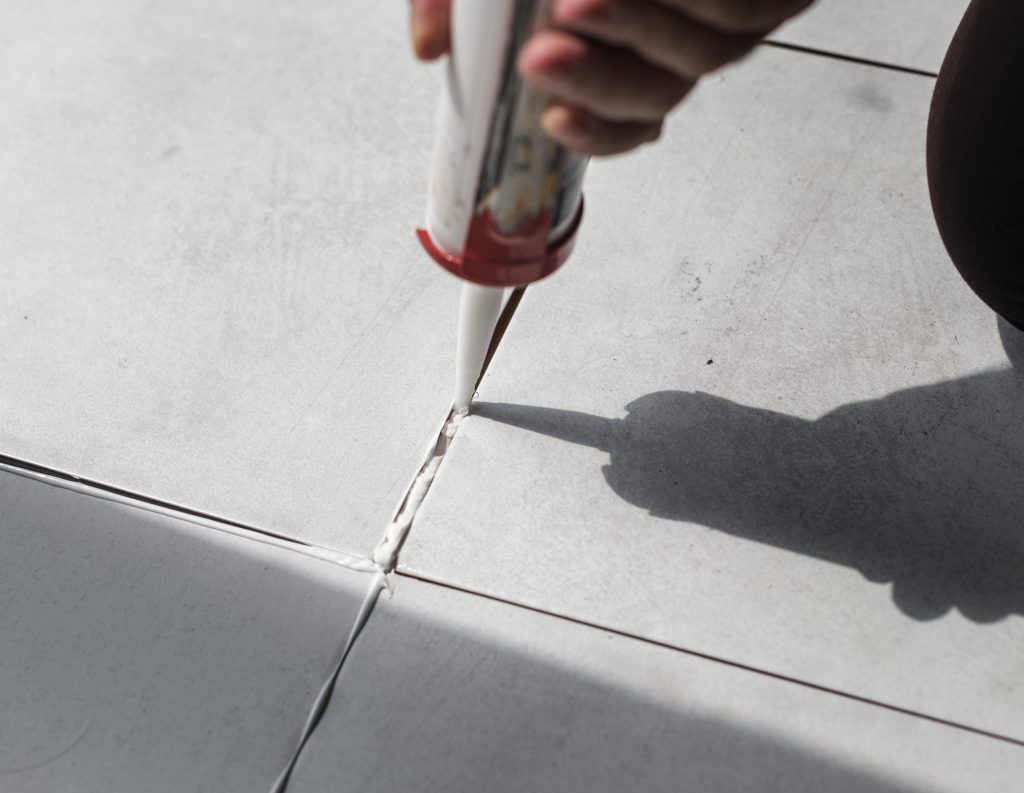 Applying silicone joint sealant to concrete floor joints with a caulking gun
