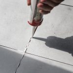 Applying silicone joint sealant to concrete floor joints with a caulking gun